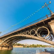 El Puente de Isabel II, conocido popularmente como Puente de Triana une el centro de la ciudad con el barrio de Triana, cruzando el río Guadalquivir. Sustituyó en el siglo XIX a un viejo puente de barcas que existía en su lugar, constituyendo el puente de hierro más antiguo conservado en España